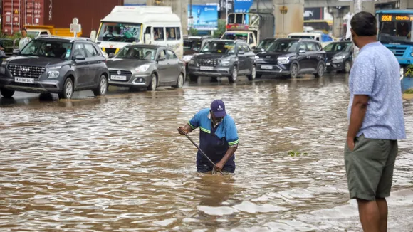 A Bruhat Bengaluru Mahanagara Palike (BBMP) worker clears the blocked drainage on a waterlogged road after rains, in Bengaluru, Sunday, Oct 20, 2024.