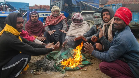People sit around a bonfire to warm themselves during a cold winter morning