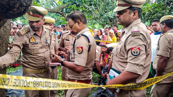 Police personnel investigate after the bodies of two girls were found hanging from a tree, at Kayamganj area in Farrukhabad, Tuesday, Aug. 27, 2024.