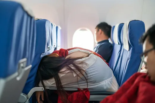 A woman with long hair folded over on an airplane