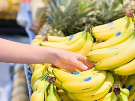 A person picks up bananas, which are a food for an upset stomach.
