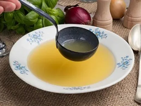 A person ladles broth, which is a food for an upset stomach, into a bowl.