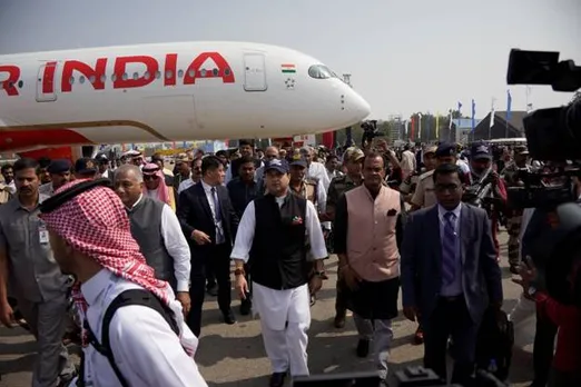 A group of people walking past an airplaneDescription automatically generated