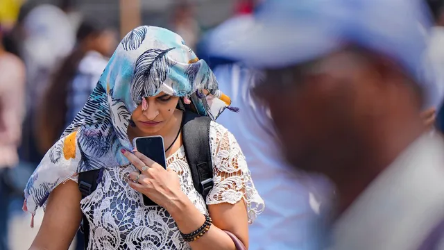 A woman covers her head with a scarf on a hot summer day