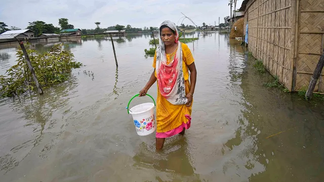 A woman walks through a flood-affected area, in Nagaon district of Assam, Tuesday, July 9, 2024