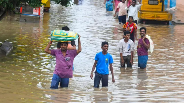 People cross a waterlogged street at the Bhavanipuram Sitara Center flood affected area, in Vijayawada, Monday, Sept. 2, 2024.