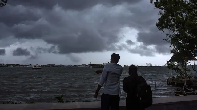 Visitors enjoy weather as dark clouds cover the city skyline during the onset of monsoon over Kerala a week later than usual, in Kochi