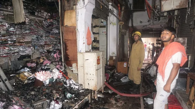 Firefighters and others stand near damaged shops after a fire broke out at Chandni Chowk on Thursday, in New Delhi, Friday, June 14, 2024.