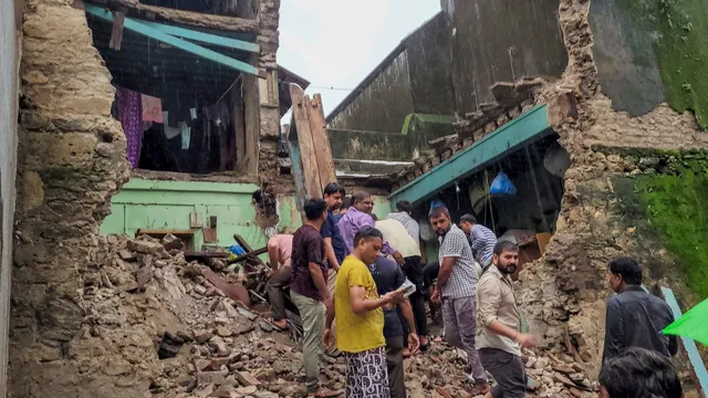 People gather after a part of a dilapidated house collapsed in Khambhalia, in Dwarka district, Tuesday, July 23, 2024.