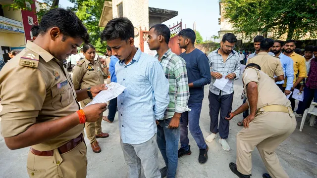 Police personnel check candidates outside an examination center before they appear for the Uttar Pradesh police recruitment examination, in Lucknow, Friday, Aug 30, 2024.