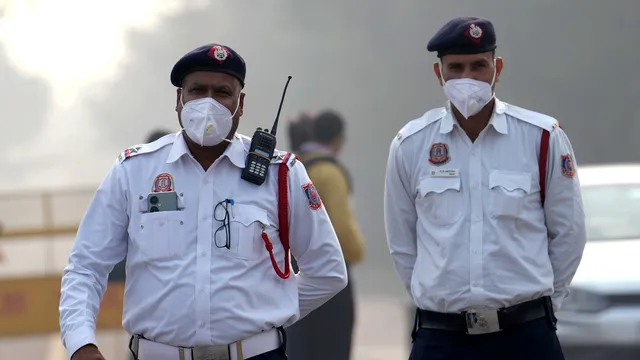 Traffic policemen wearing an anti-pollution mask regulate vehicular movement, in New Delhi