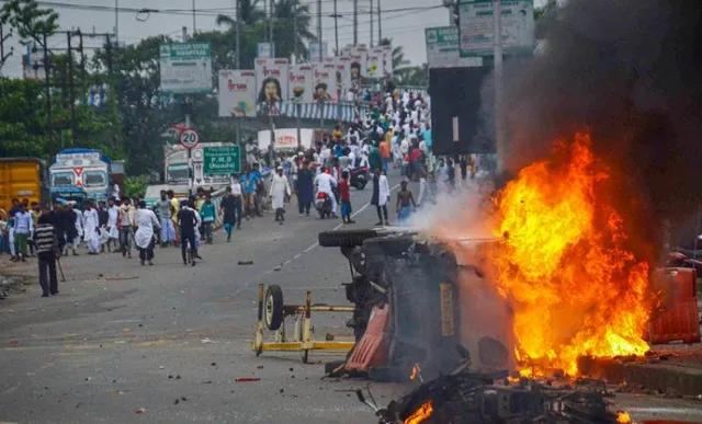 Flames and smoke rise from a vehicle on fire torched by rioters