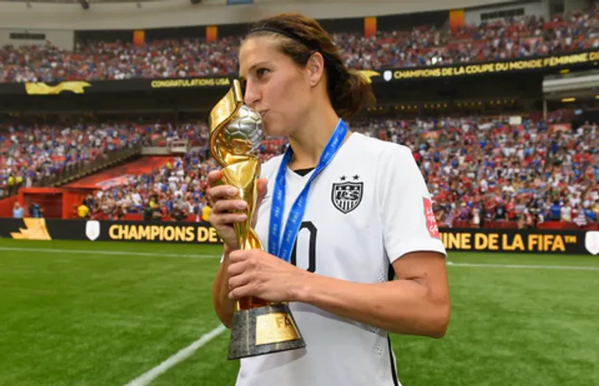 Retired female football veteran Carli holding a world cup trophy- Sportz Point.com