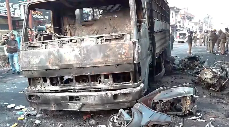 Charred remains of vehicles lie on a road after local residents on Thursday set vehicles and a police station on fire and hurled stones