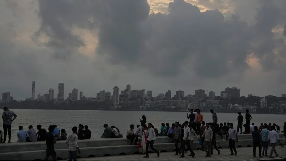 People enjoy at the sea front as dark clouds engulf the sky, in Mumbai, Sunday, June 9, 2024.