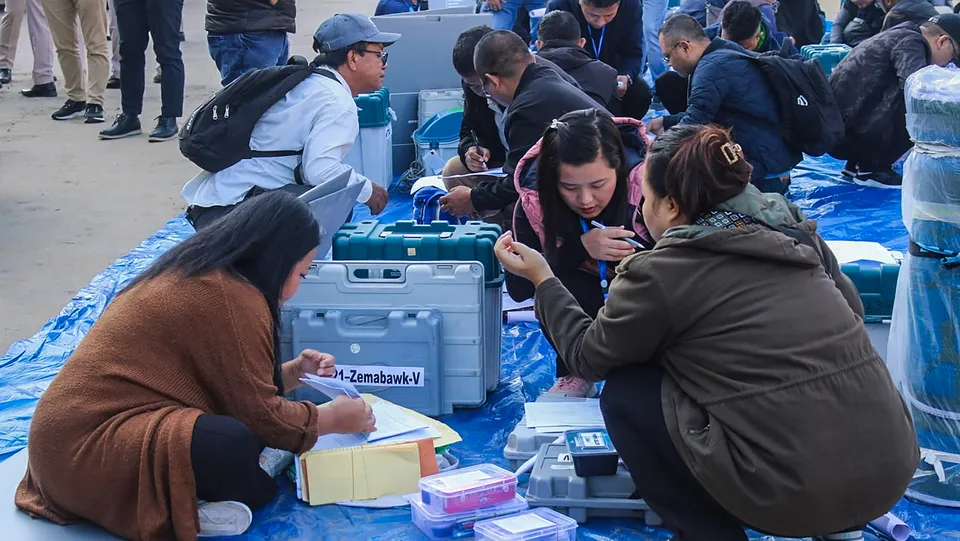 Polling officials collect EVMs and other election material at a distribution centre ahead of voting for Mizoram Assembly elections